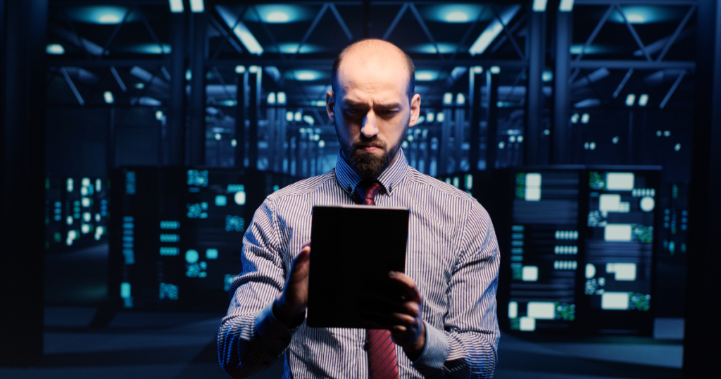 man standing with a tablet in a server room representing a disaster recovery plan
